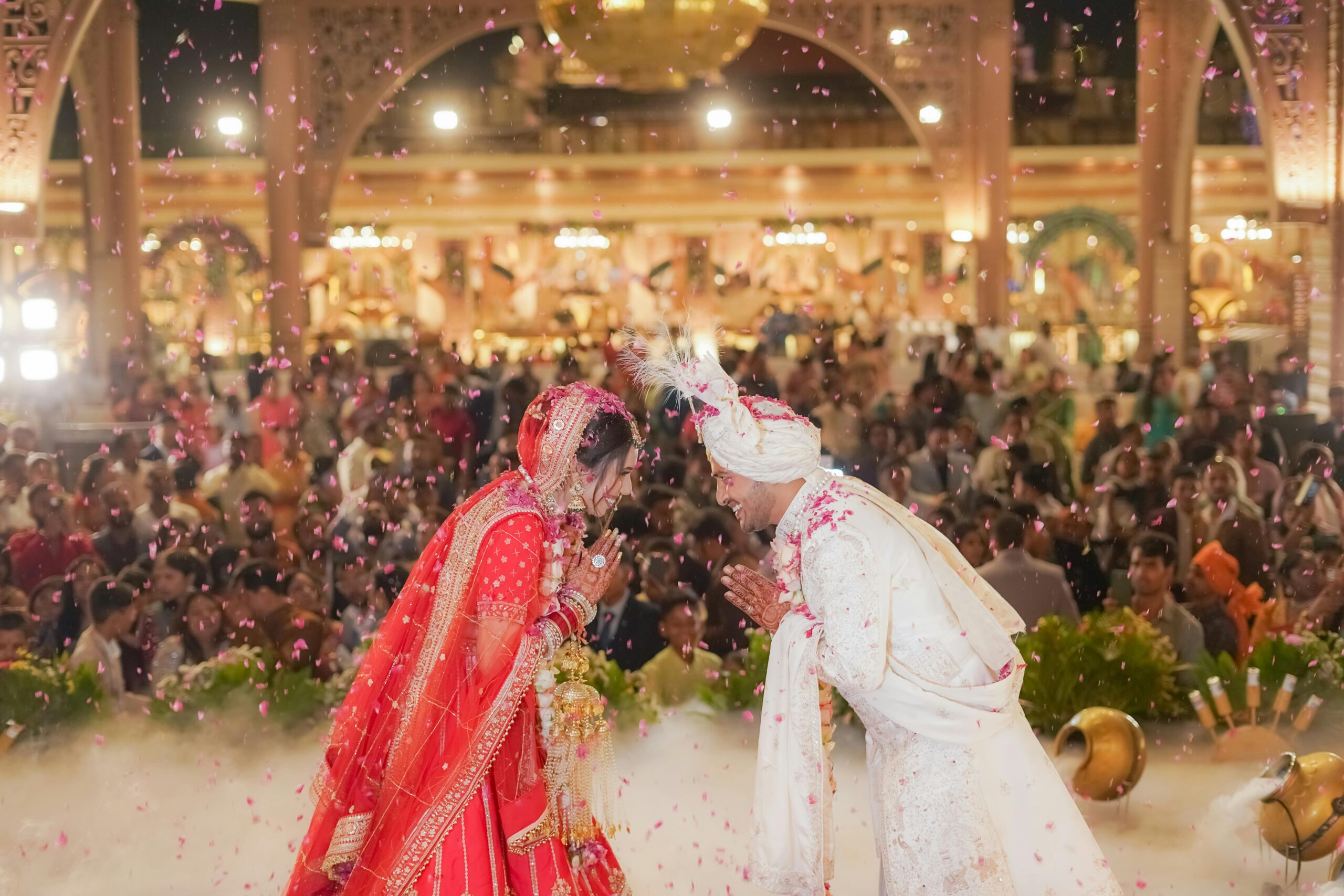 Bride and groom in traditional attire celebrating their wedding with a bow in Delhi, India.